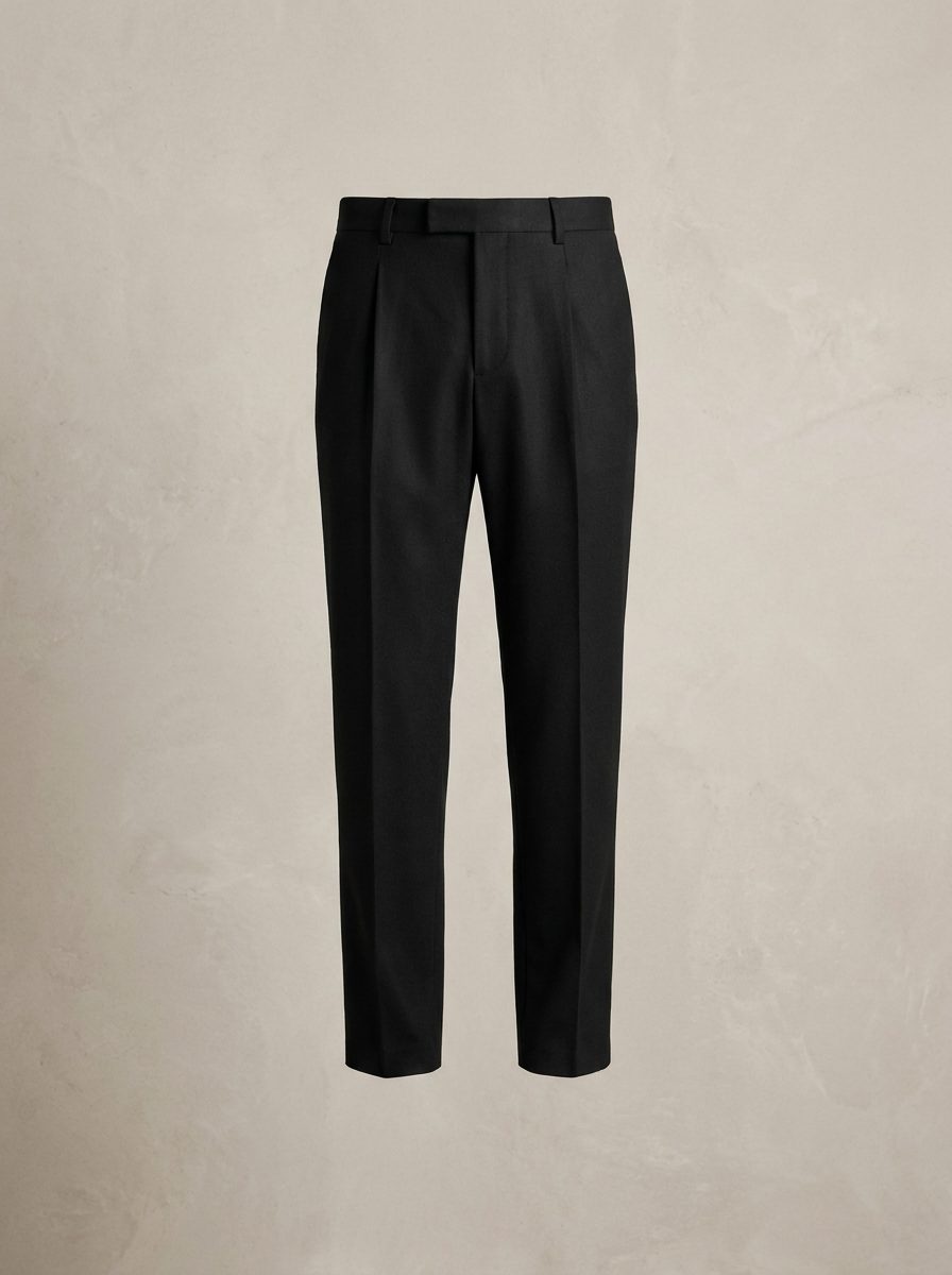 Black pleated wool trousers for men on a warm off-white background