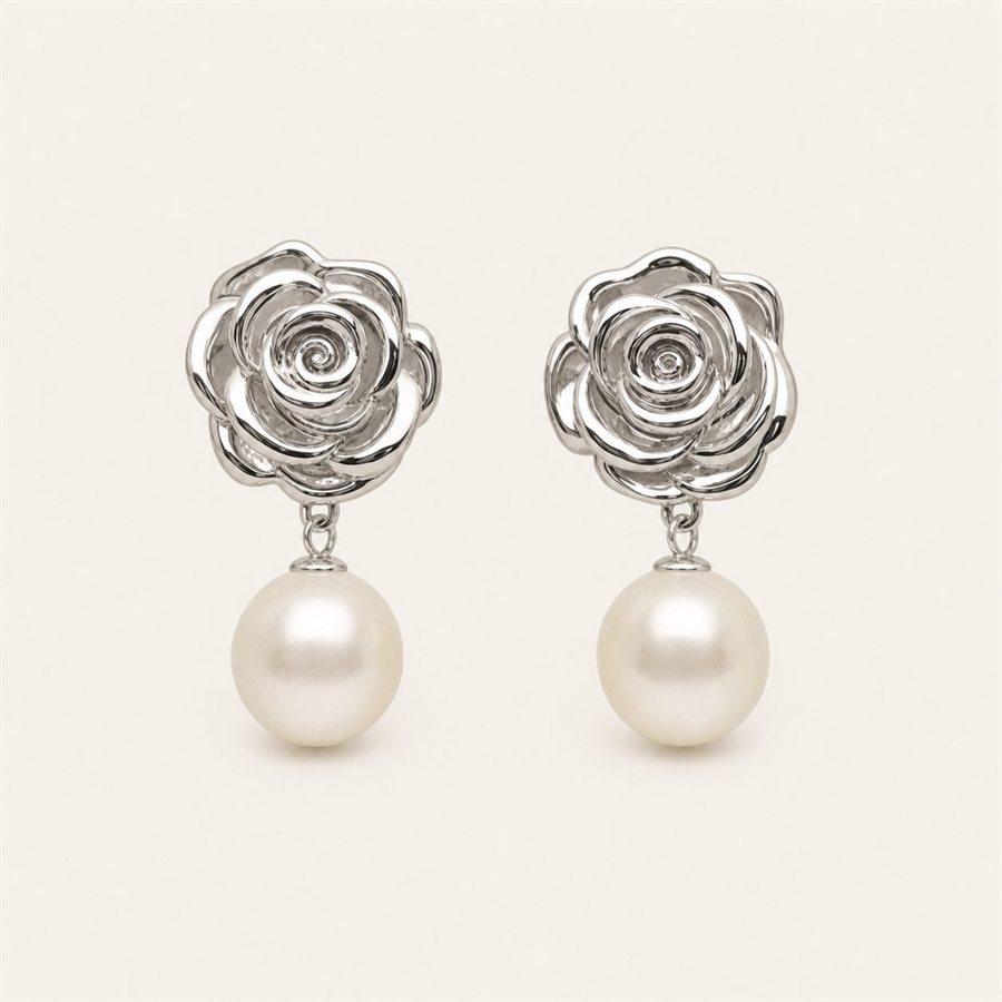 Silver rose pearl earrings on a warm off-white background